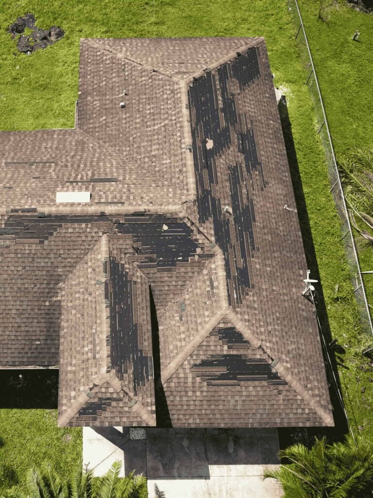 Aerial drone view of residential asphalt shingle roof showing worn and damaged areas during a professional roof inspection by Dinosaur Roofing & Repair, helping homeowners identify issues early and protect their property in Middle Georgia.
